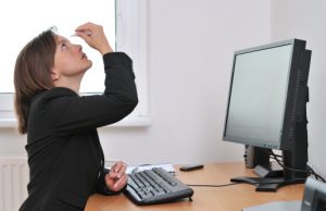 Young business person applying eyes drops