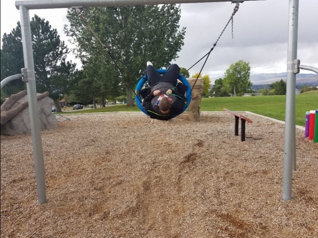 Young man swinging high in saucer-shaped swing.