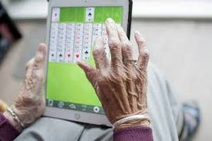 Older woman's hands playing solitaire on iPad.