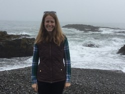 Kelsey Lastowski stands on a stormy, rocky beach.