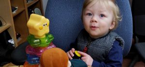 Two-year-old boy presses button to activate toy, making ooo face.